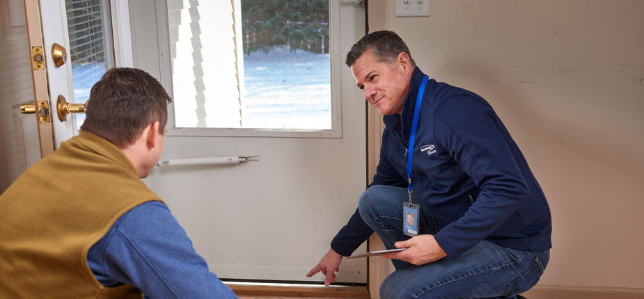 Consumers energy worker pointing out air leaking from an unsealed screen door. 
